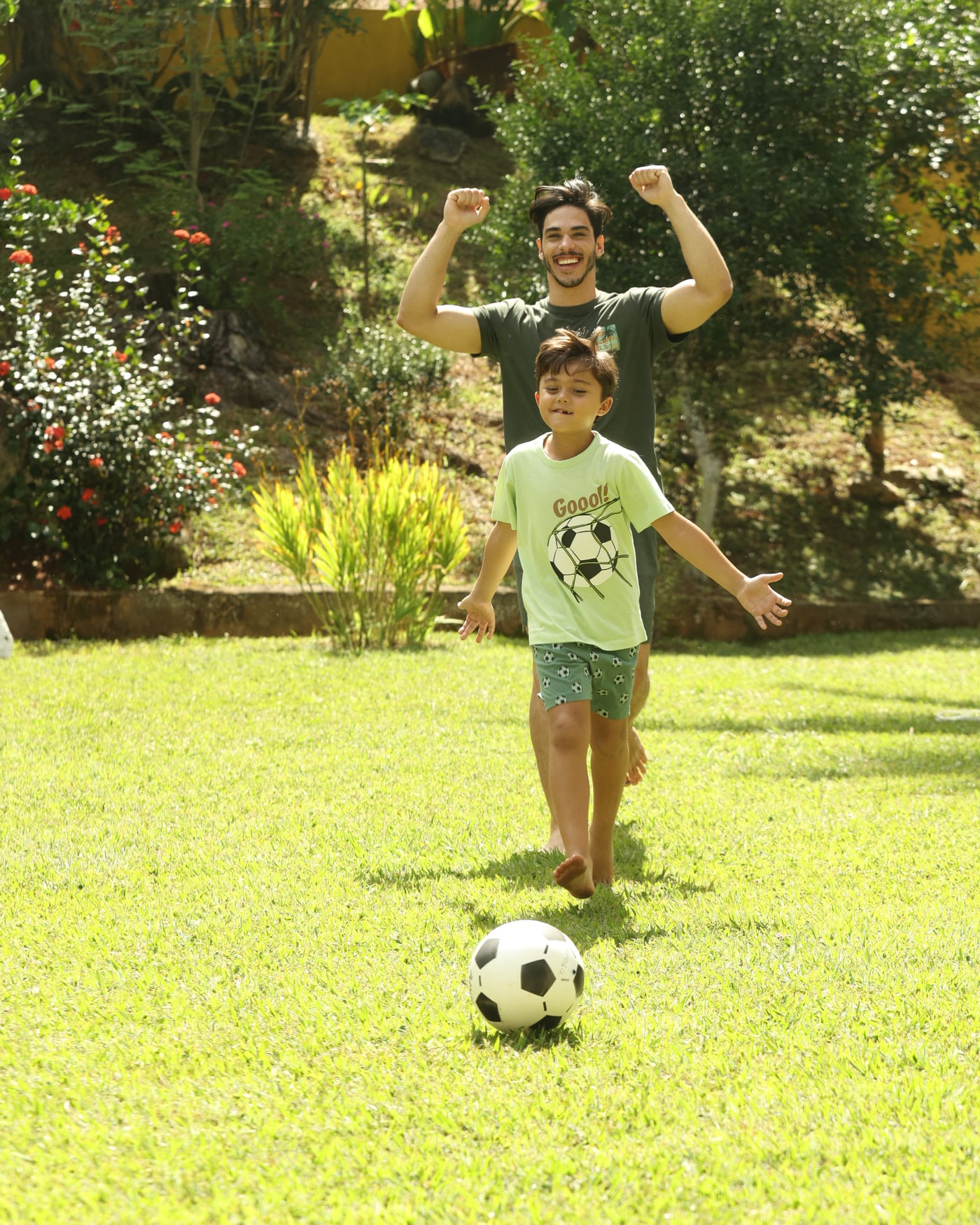 Menino de pijama verde com estampa de futebol correndo atrás da bola