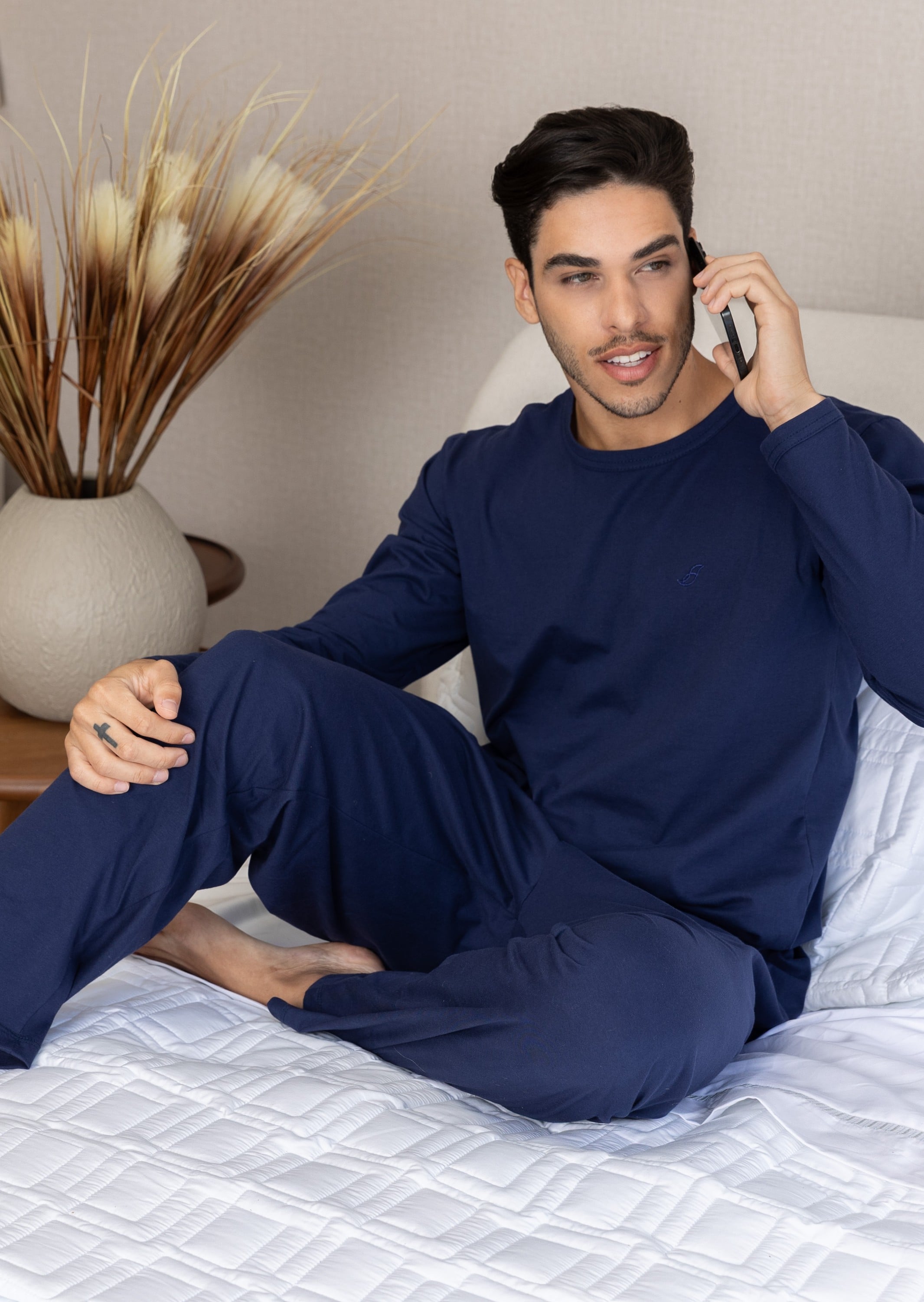 Homem de pijama azul-marinho sentado na cama, coleção Sintonia